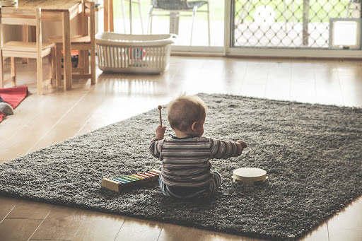 infant on rug playing drum