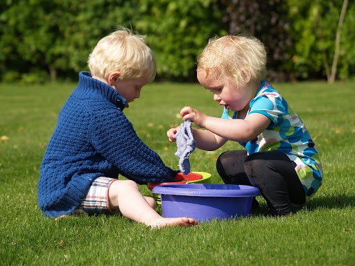 2 kids playing with wash tub outside play therapy activities