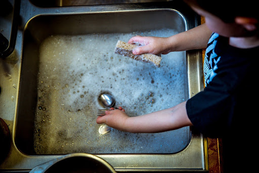 child washing dishes in sink with soapy water play therapy activities