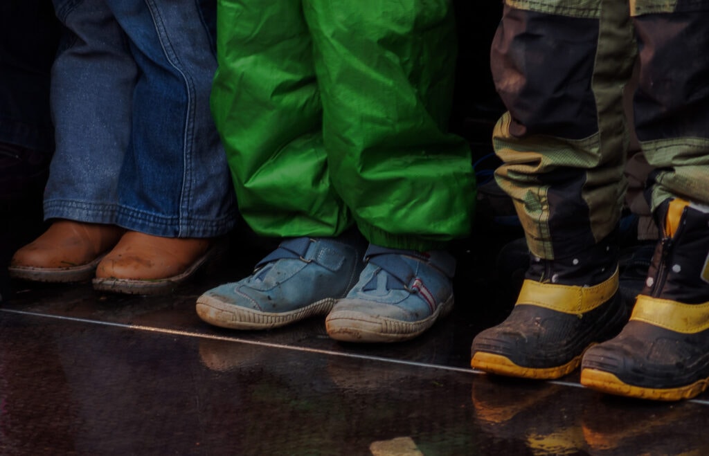 legs and feet of 3 kid with shoes and boots
