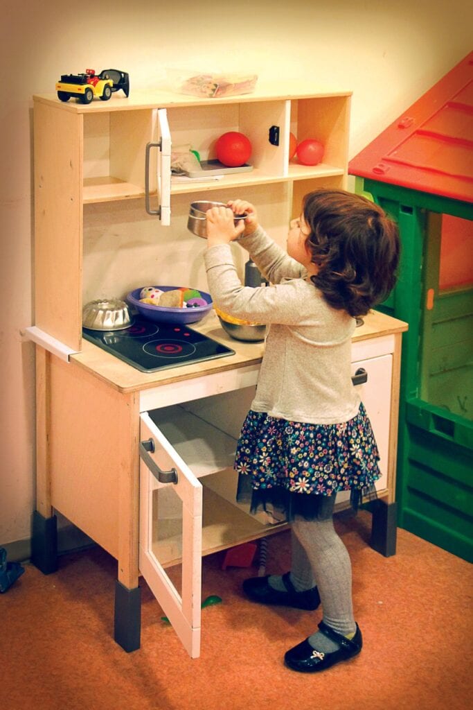 child with play kitchen